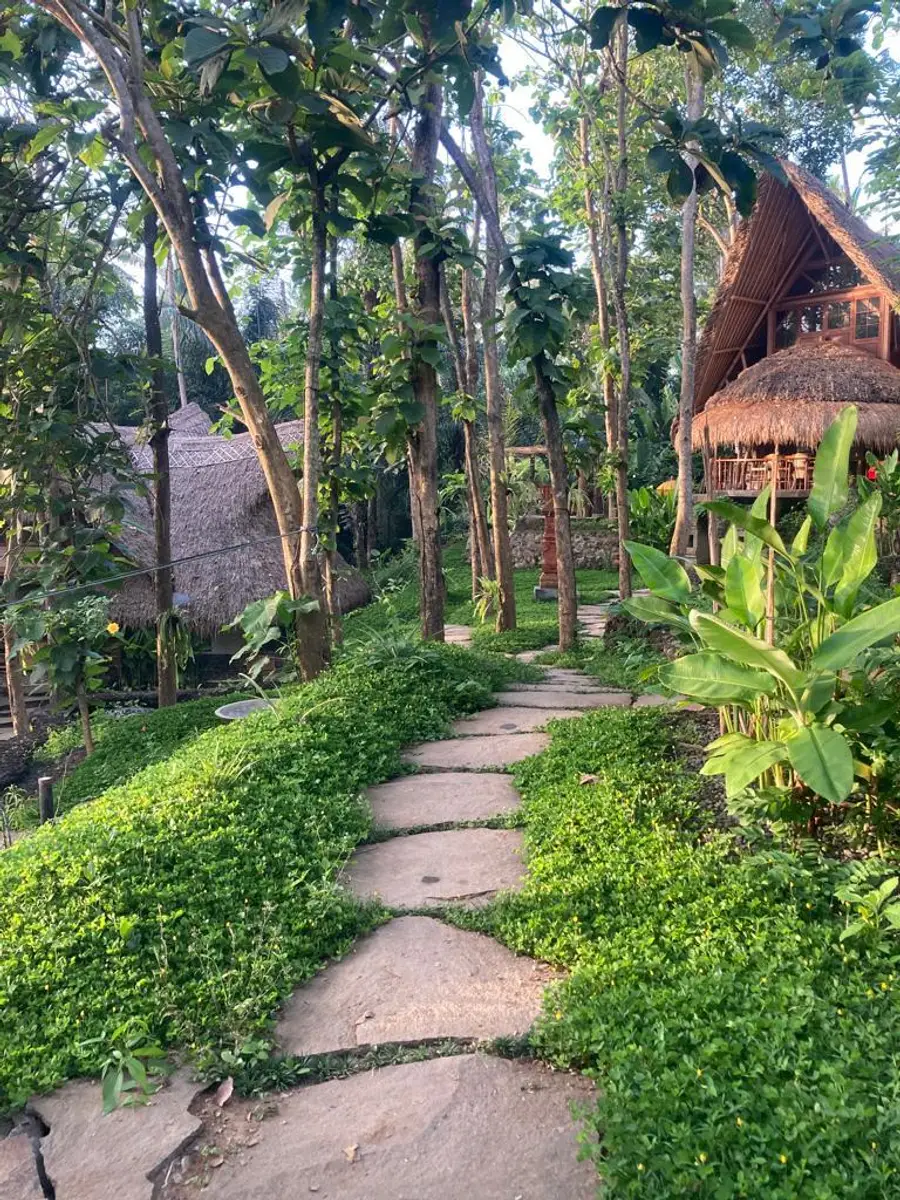 Stone pathway winding through the jungle past thatched-roof villas