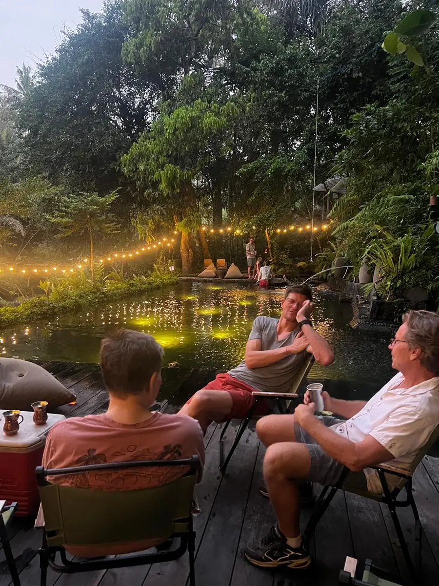 Friends relaxing by the natural pool in the evening